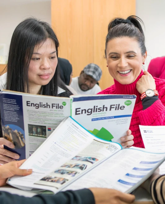 A group of students sits together reviewing English language learning materials, including textbooks titled "English File," in a classroom setting. A group of students sits together reviewing English language learning materials, including textbooks titled "English File," in a classroom setting.